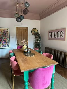 a dining room table with pink and green chairs