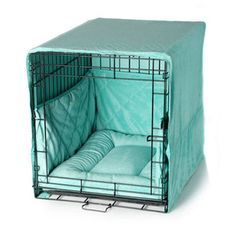 a dog crate with a cover over it's bed and pillows on the side