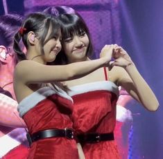 two girls in red dresses are hugging each other on stage with their arms around one another