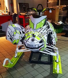 a green and white snowmobile parked on top of a tile floor in a room