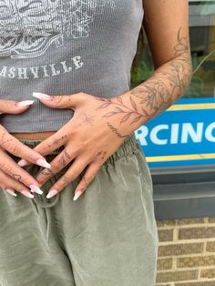 a woman with tattoos on her arms and hands is standing in front of a store