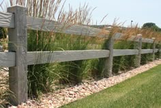 a wooden fence surrounded by grass and rocks