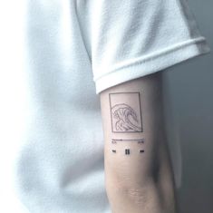 a person wearing a white shirt with a tattoo on their arm that has an image of a wave in it