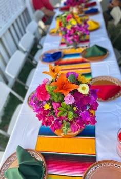 the table is set with colorful plates and flowers