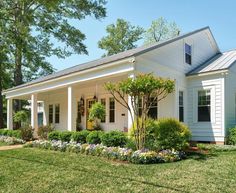 a white house sitting on top of a lush green field next to trees and bushes