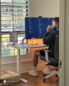 a man sitting at a desk in front of a computer monitor with the screen turned on