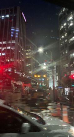 cars driving down the street at night in traffic lights and skyscrapers are visible behind them