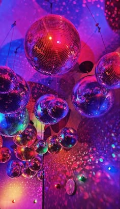 several disco balls hanging from the ceiling in front of purple and blue lights with stars on them