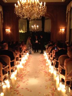 a bride and groom standing in front of an aisle filled with candles