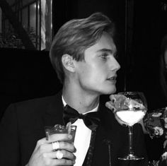 two people in tuxedos are drinking wine