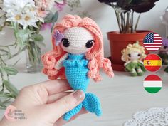 a crocheted little mermaid doll sitting on top of a table next to flowers