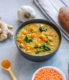 a bowl of soup with carrots, broccoli and other ingredients next to it