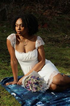 a woman is sitting on a blanket holding a bouquet