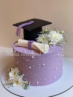 a purple cake with white flowers and a graduation cap on top