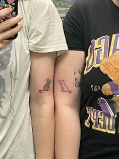 two people standing next to each other with tattoos on their arms