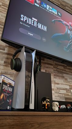 a large screen tv mounted on the wall above a shelf with video game controllers and games