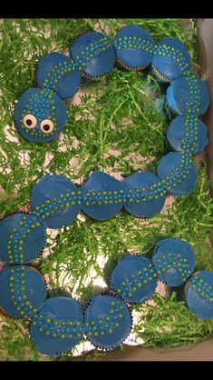 cupcakes with blue icing and green grass in the shape of a caterpillar