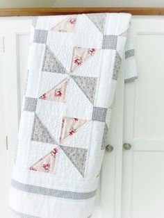 a quilted blanket hanging on the side of a white cabinet next to a door