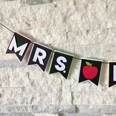 an apple themed banner hanging on a brick wall with the word mr and mrs spelled in large letters