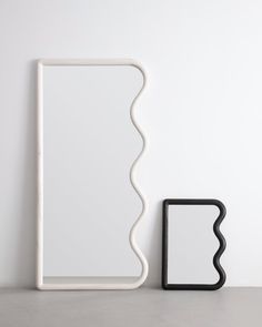 a white and black object sitting on top of a table next to a square mirror