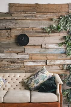 a couch sitting in front of a wooden wall with a clock on it's side