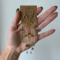 "Solar system hand earrings are handcrafted from solid brass.  Earring approx. 5\" long and 1\" across.  0.1oz weight Hangs from brass or sterling fish hook earring. Choose in variations.  crystals include: hematite, sodalite, carnelian, jasper, Howlite, agate, tigers eye, labradorite Crystal selections subject to substitutions depending on available selection but rest assured, the perfect unique crystal will be chosen for your piece.  Coloring of crystals may vary. All metals used by Pop & Locket are nickel free and hypoallergenic.  Each order comes beautifully packaged in a kraft paper pillow box with a laurel leaf for luck and a intuitively picked polished palm crystal.   Write a positive intention on your leaf and burn it for manifestation of your intention. Pop & Locket is green eco f Brass Chandelier Dangle Earrings, Brass Chandelier Earrings With Dangling Beads As Gift, Brass Dangle Chandelier Earrings, Gold Crystal Earrings Nickel Free, Handmade Celestial Crystal Earrings For Gift, Spiritual Dangle Crystal Earrings With Ear Wire, Handmade Witchy Earrings For Gift, Adjustable Wire Wrapped Spiritual Earrings, Wire Wrapped Brass Chandelier Dangle Earrings