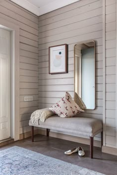 a room with a bench, mirror and slippers on the floor in front of it