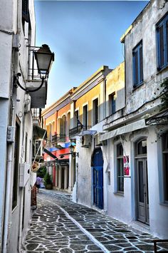 an empty street with buildings and people walking on the side walk in front of them