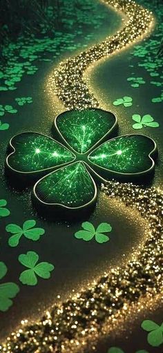 four leaf clovers are on the ground with gold glitter and green leaves in the background