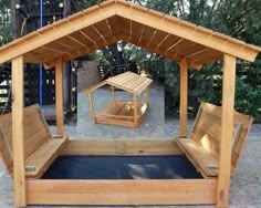 a wooden gazebo in the middle of a park with benches and a picnic table