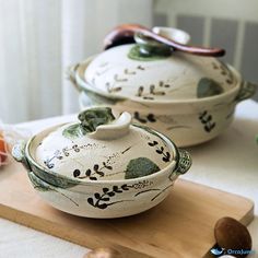 two ceramic dishes sitting on top of a cutting board