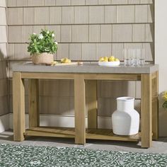 a table with two white vases and lemons on it in front of a brick wall