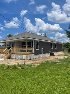 a small gray house sitting on top of a lush green field under a blue sky