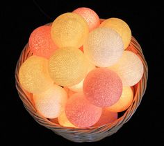 a basket filled with lots of different colored balls on top of a table next to a black background