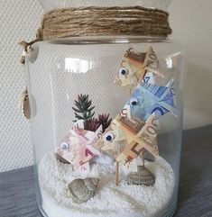 a glass jar filled with lots of different types of paper fish and plants in it