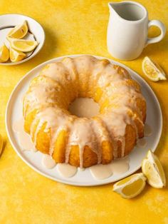 a lemon bunt cake with icing on a plate next to sliced lemons