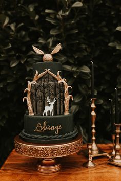 a three tiered cake decorated with deer and antlers is on a table next to candles