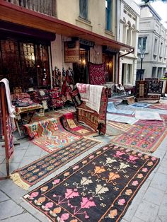 many rugs are on the ground in front of shops