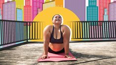 a woman is doing yoga outside in front of a cityscape with skyscrapers