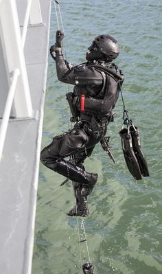 a man in diving gear is hanging off the side of a boat