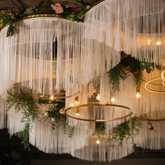 the chandelier is hanging from the ceiling and decorated with greenery, candles and flowers