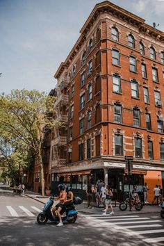 people crossing the street in front of an old brick building