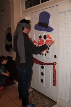 a man wearing a hat and scarf making a snowman door decoration