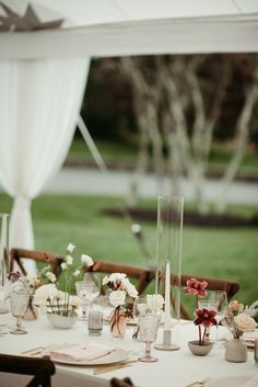 the table is set with flowers, candles and napkins for an outdoor wedding reception