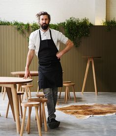 a man in an apron standing next to a table