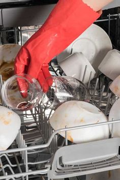 a person in red gloves is reaching into the dishwasher full of dirty dishes