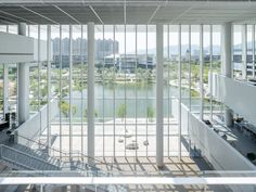 the interior of an office building with glass walls and floor to ceiling windows, overlooking a body of water