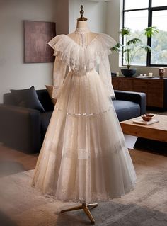 a dress on display in front of a window with a couch and table behind it