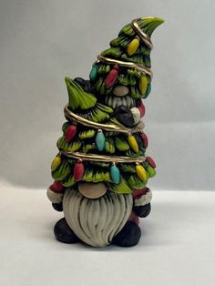 a small christmas tree made out of glass beads and other items on a white surface