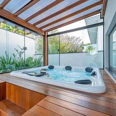 a large hot tub sitting on top of a wooden floor next to a glass wall